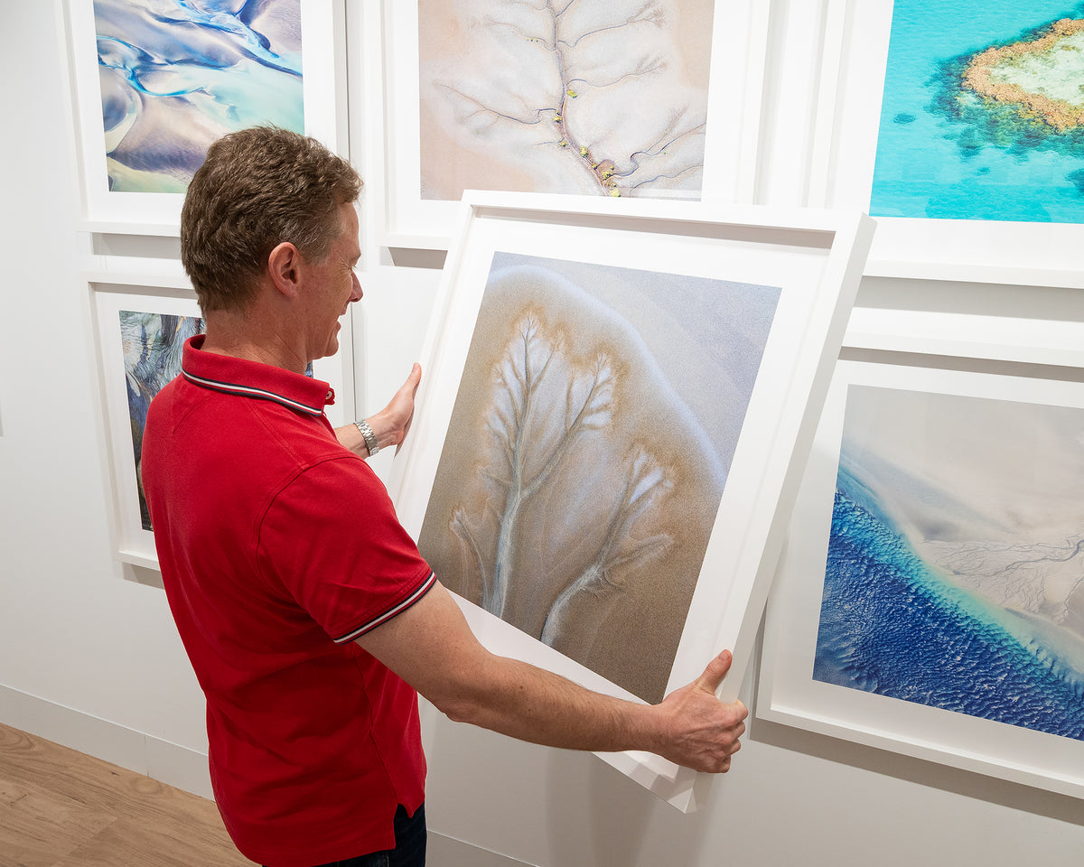 Spread. Aerial artwork of tidal patterns Cambridge Gulf, The Kimberley, held in hands ready to hang in gallery.