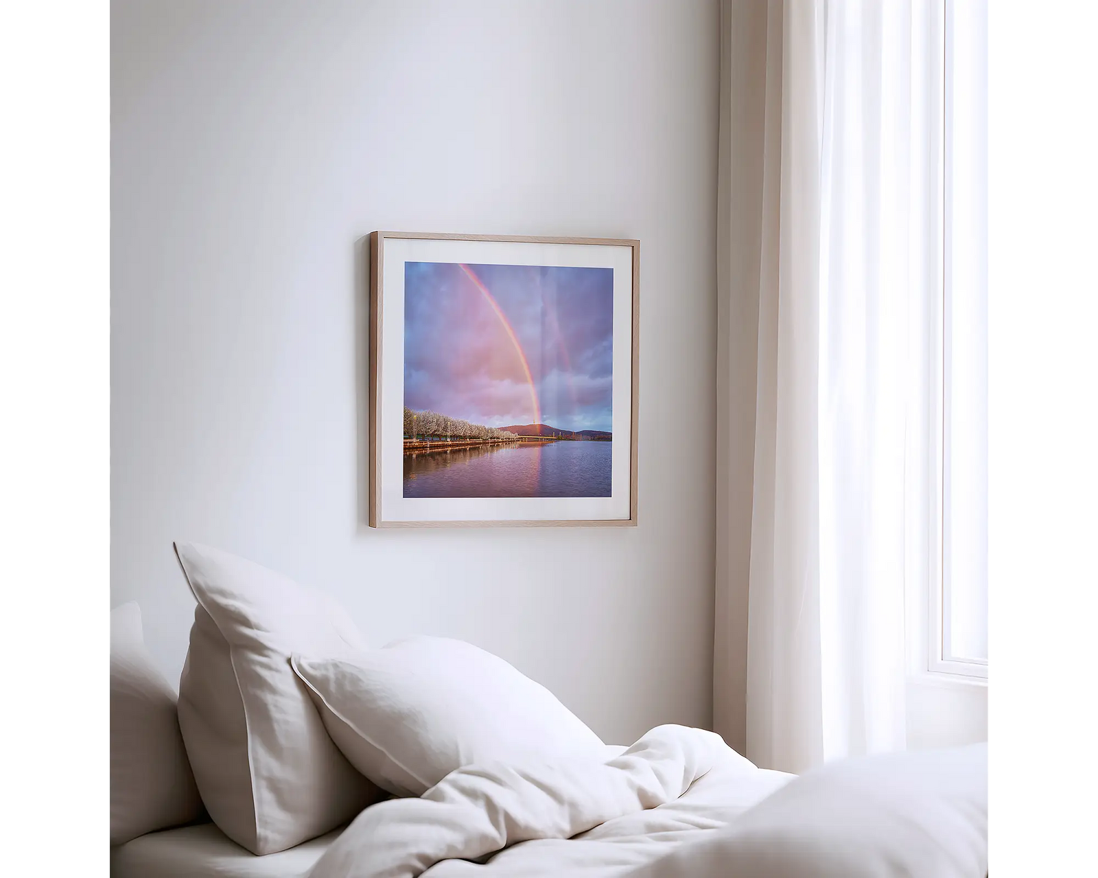 Framed photograph of a double rainbow over Lake Burley Griffin with trees and mountains in the background.