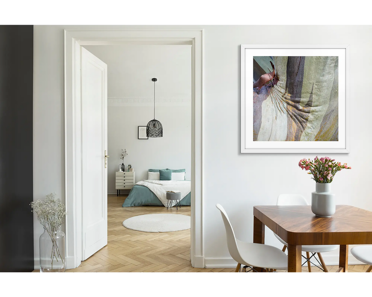 Squish. Abstract wall art print of snow gum bark on Mount Buller, framed with a white fame and hung near a wooden dining table. 