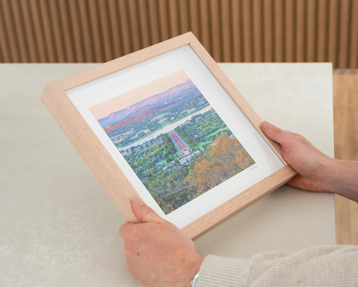 State of Flux. Canberra sunrise wall art print with timber frame being held in hands.