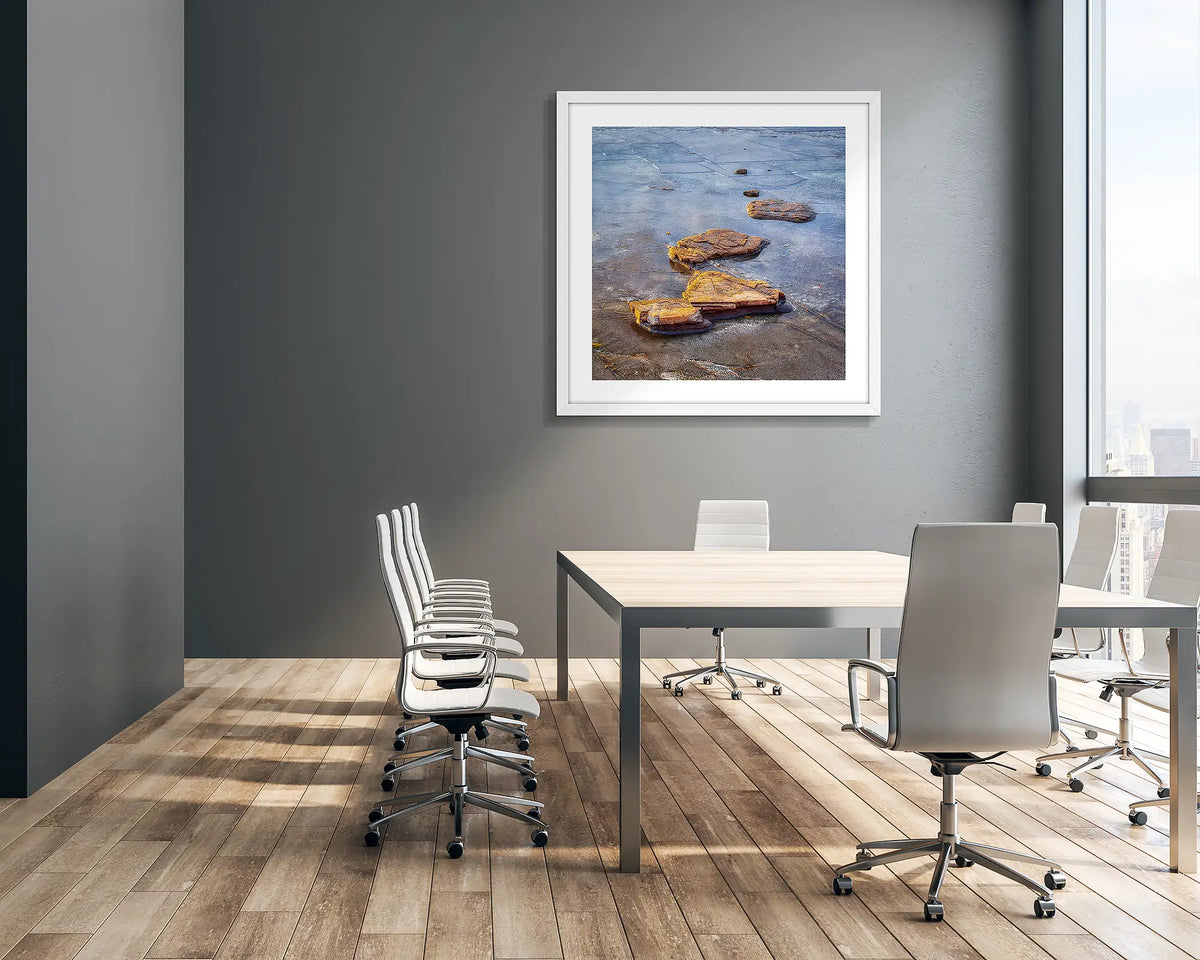 Stepping Stones. Coastal rocks, wall art print in a white frame hung in an office meeting room. 