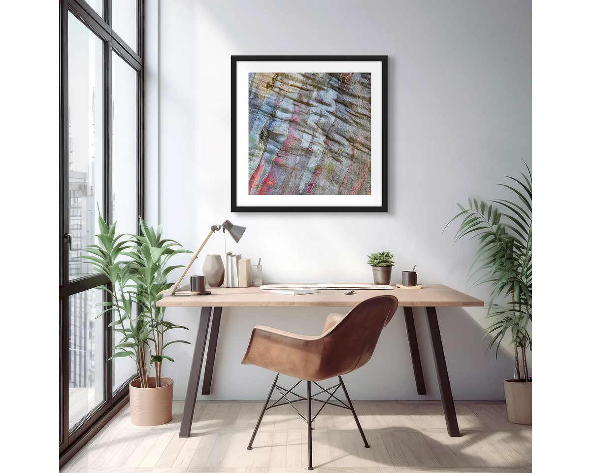 Stirling Colours. Abstract wall art print of colours in snow gum bark, with a black frame, hung on an apartment wall above a small desk.
