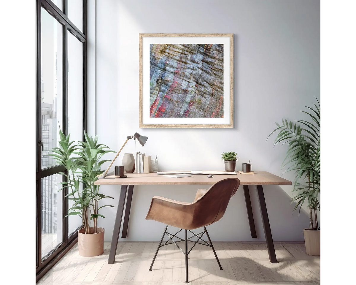 Stirling Colours. Abstract wall art print of colours in snow gum bark, with a timber frame, hung on an apartment wall above a small desk.