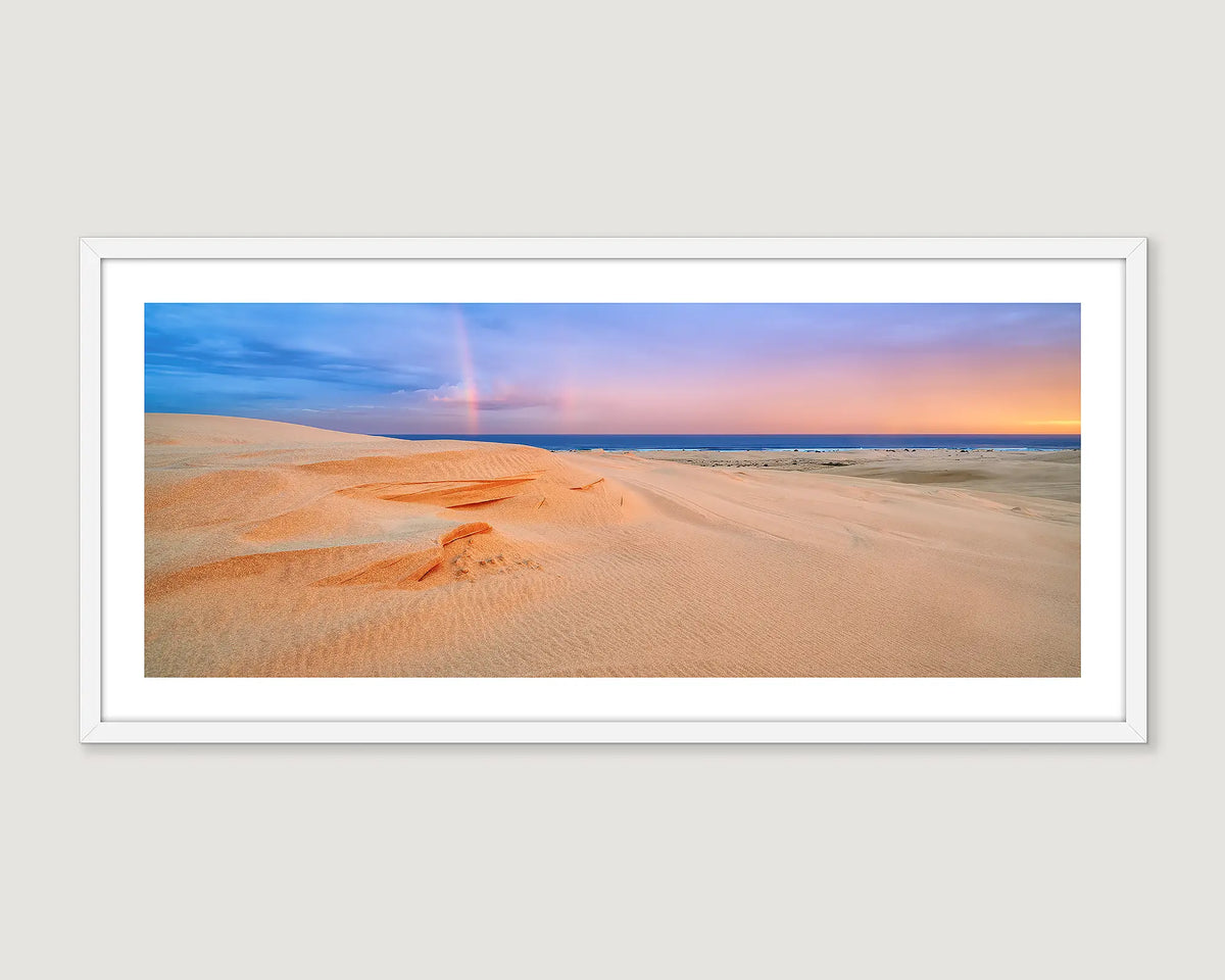 Framed coastal photograph of ocean waves, and sand dunes with a sunset sky.