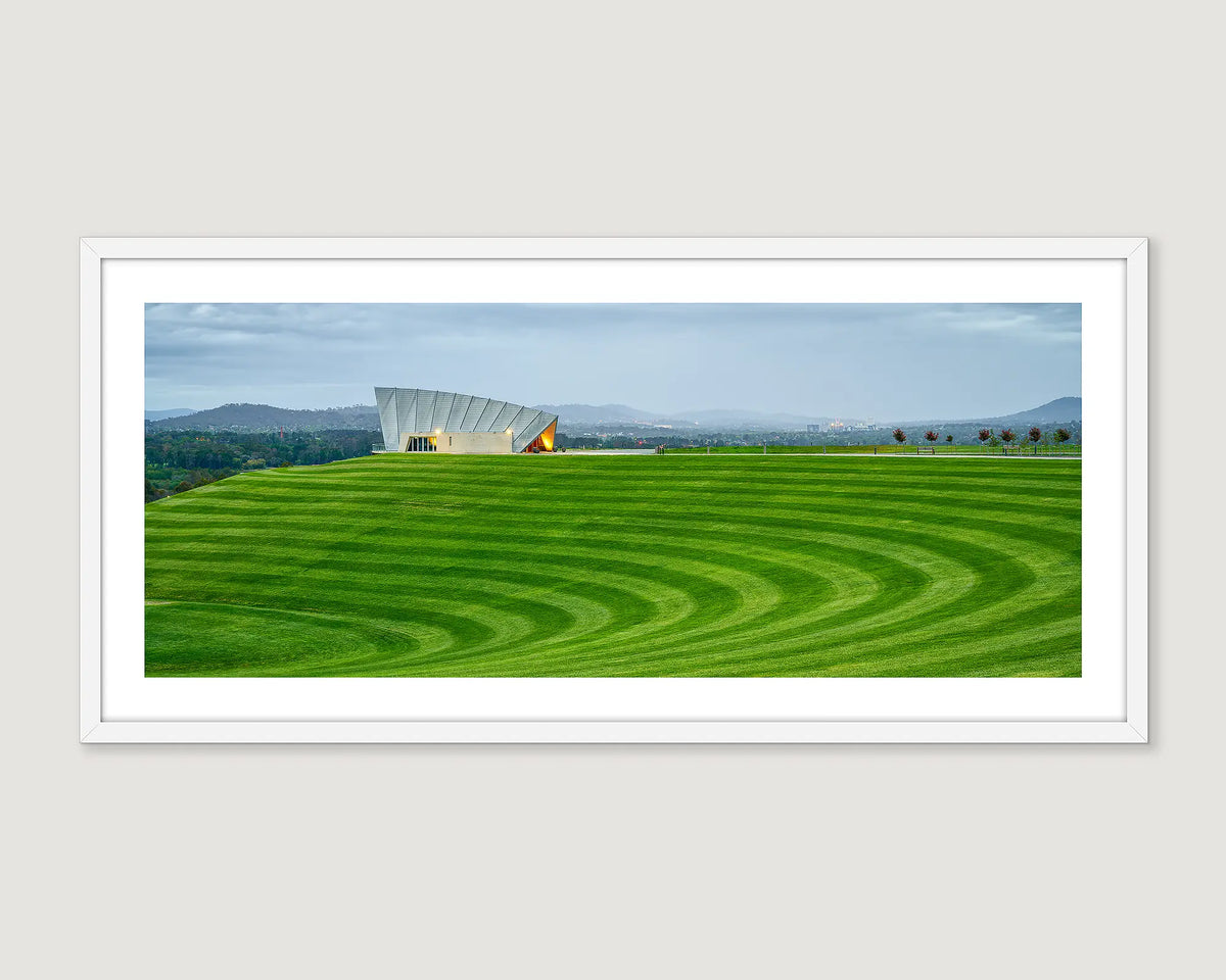 Modern building with a green field and mountains in the background at the National Arboretum.