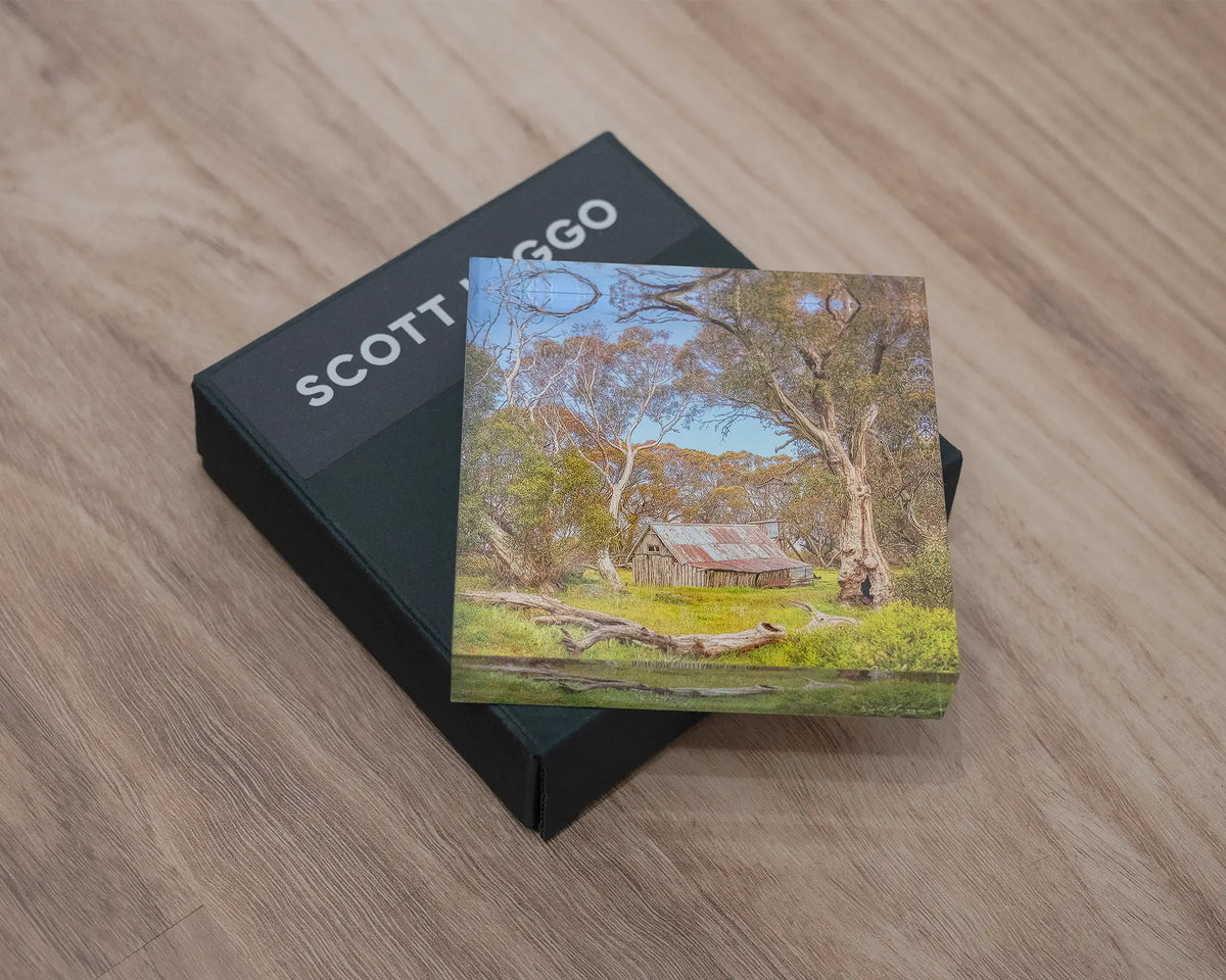 Summer in the High Country. Acrylic block of Wallace Hut, Victoria, laying flat on a gift box, on a desk.