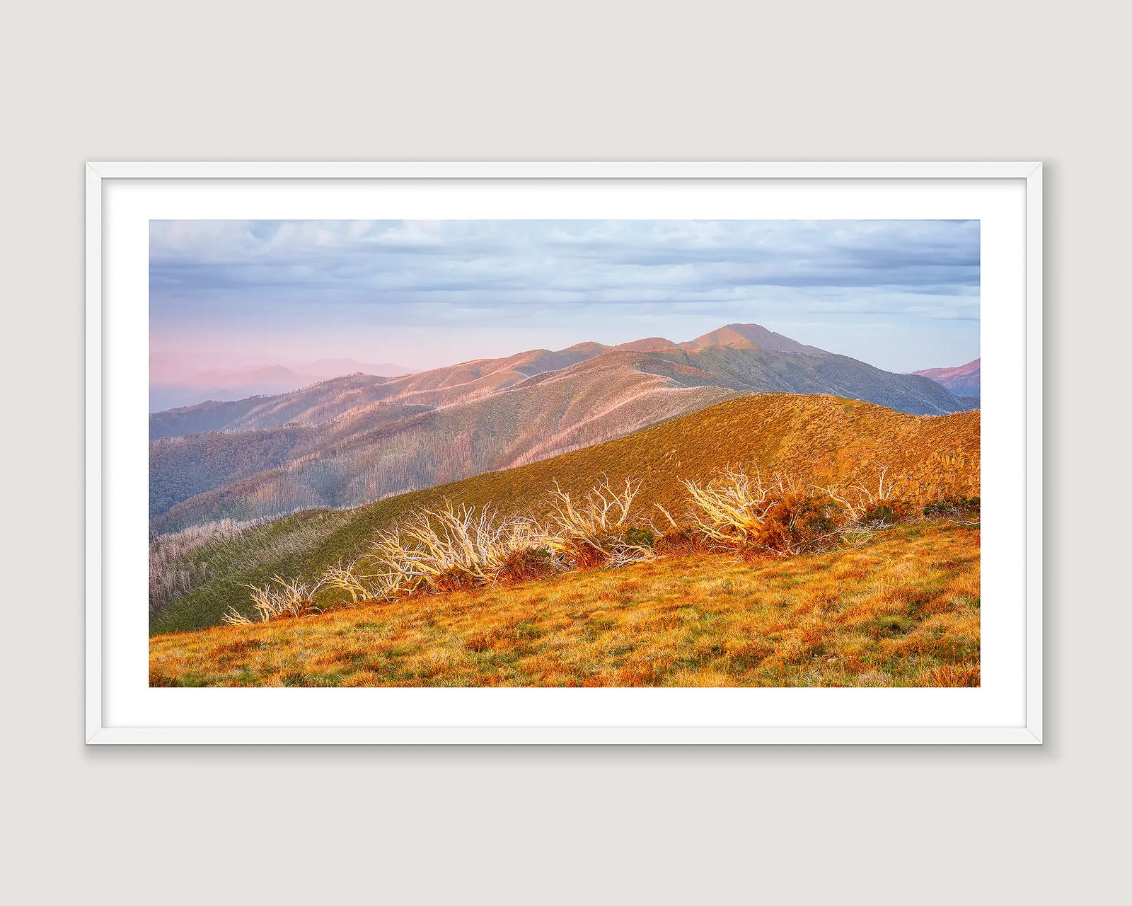 A framed landscape art print depicting sunset over Mount Feathertop, presented in a white frame against a light grey background.