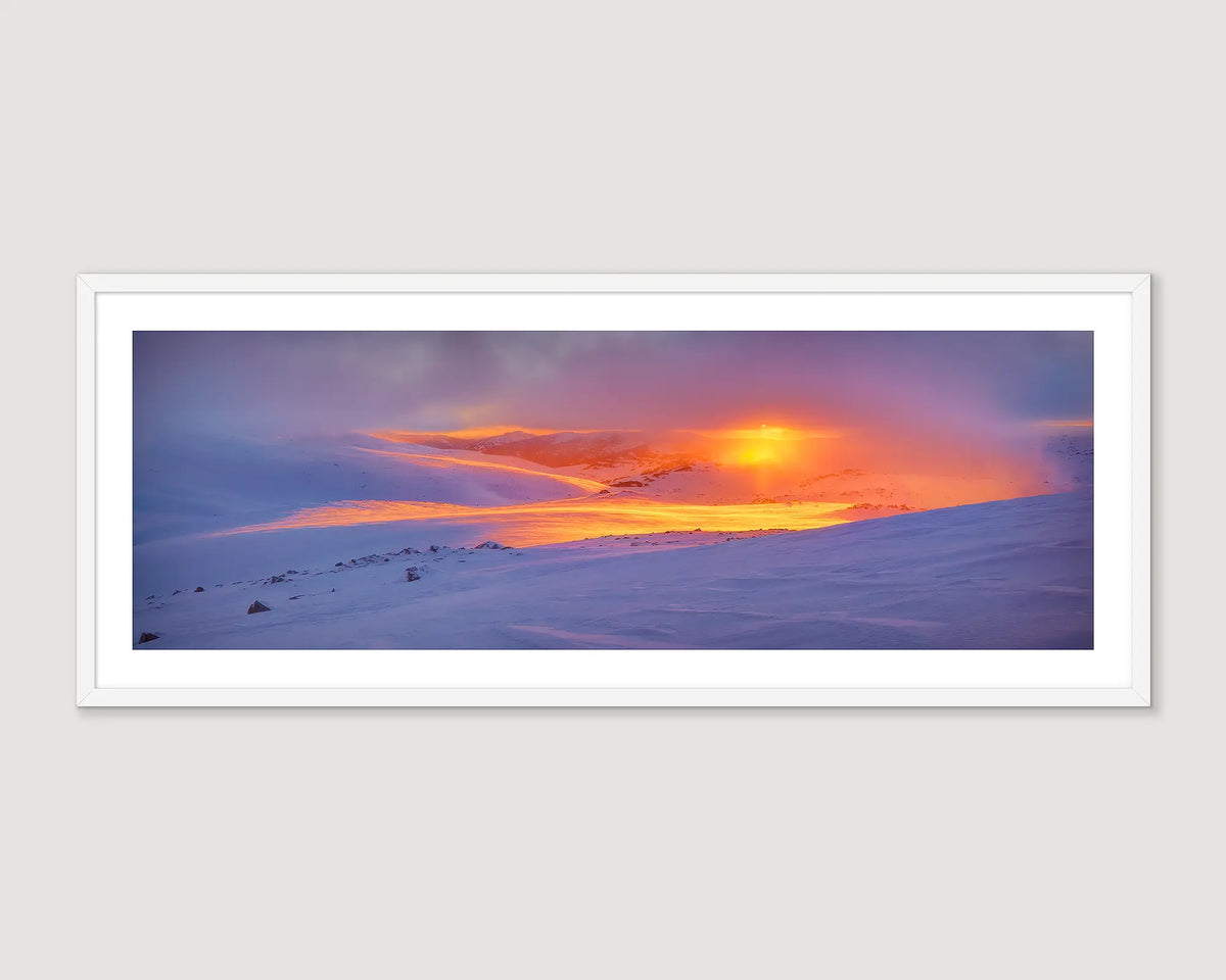 Framed artwork of a snowy landscape with a vibrant sunset.