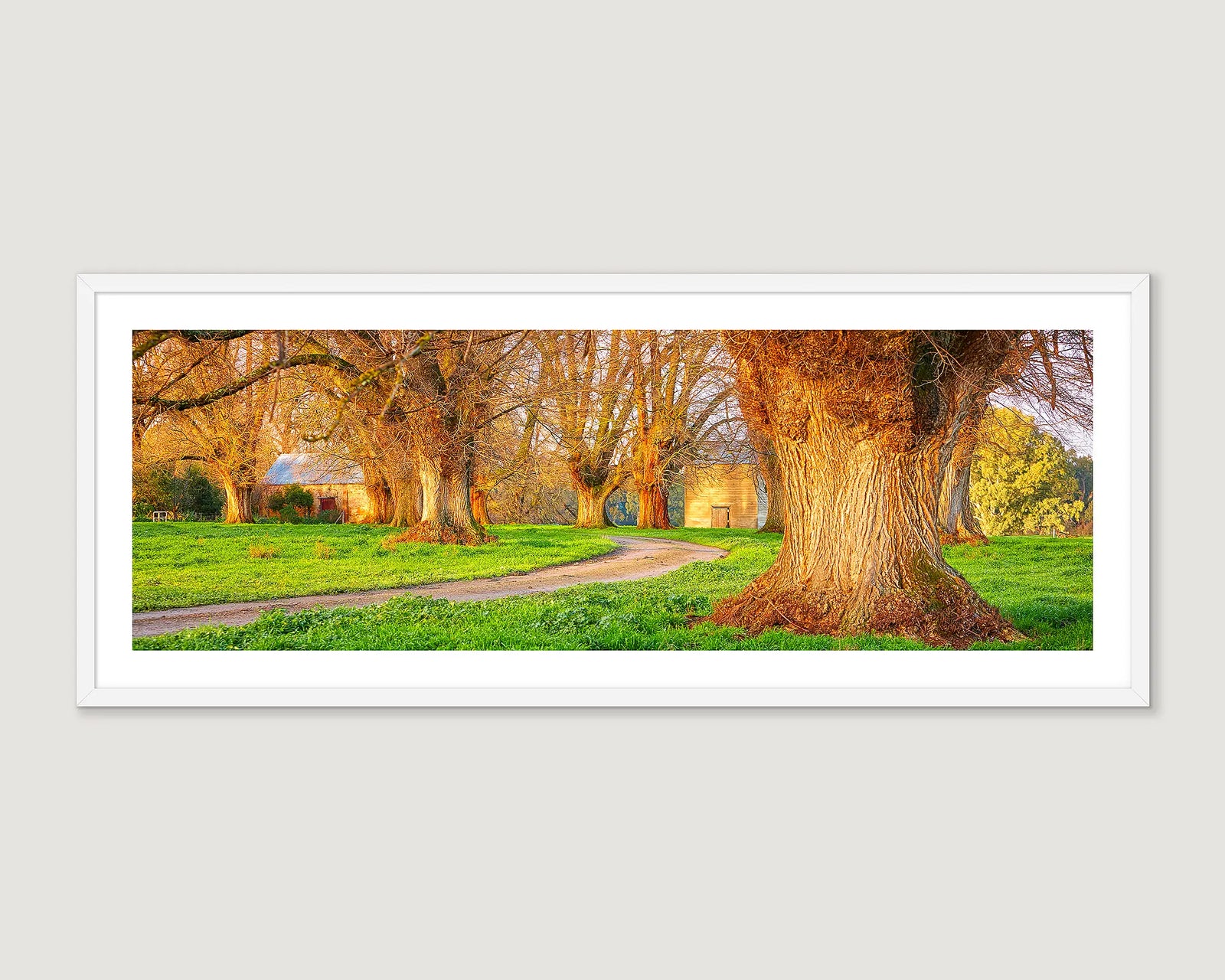 Framed artwork of a scenic landscape with a historic building, trees and a path.