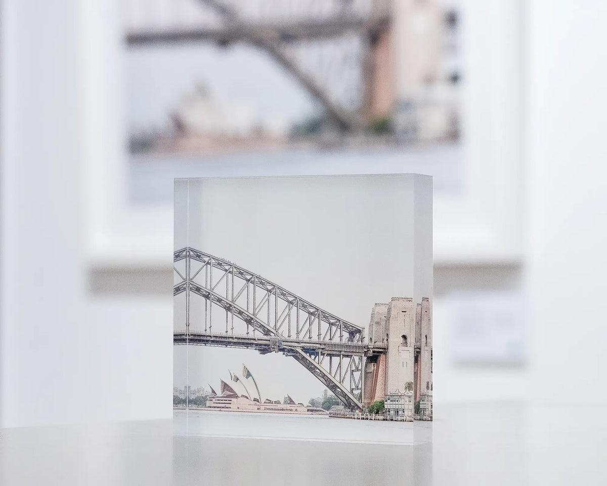 Sydney Icons. Acrylic block of Sydney Opera House and Harbour Bridge, in gallery with large SYDNEY ICONS wall art in background.