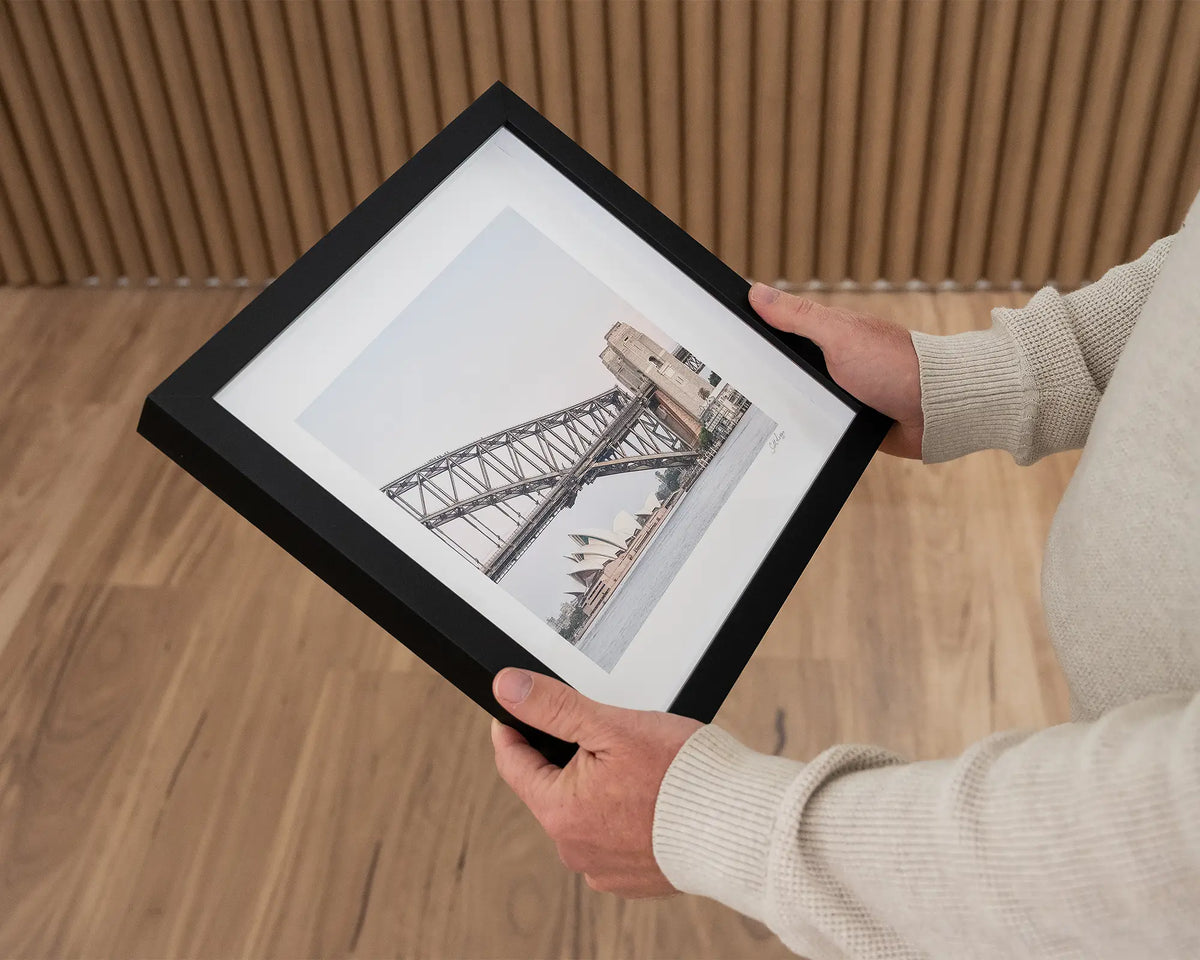 Sydney Icons. Harbour Bridge and Opera House small print with black frame, held in hands.