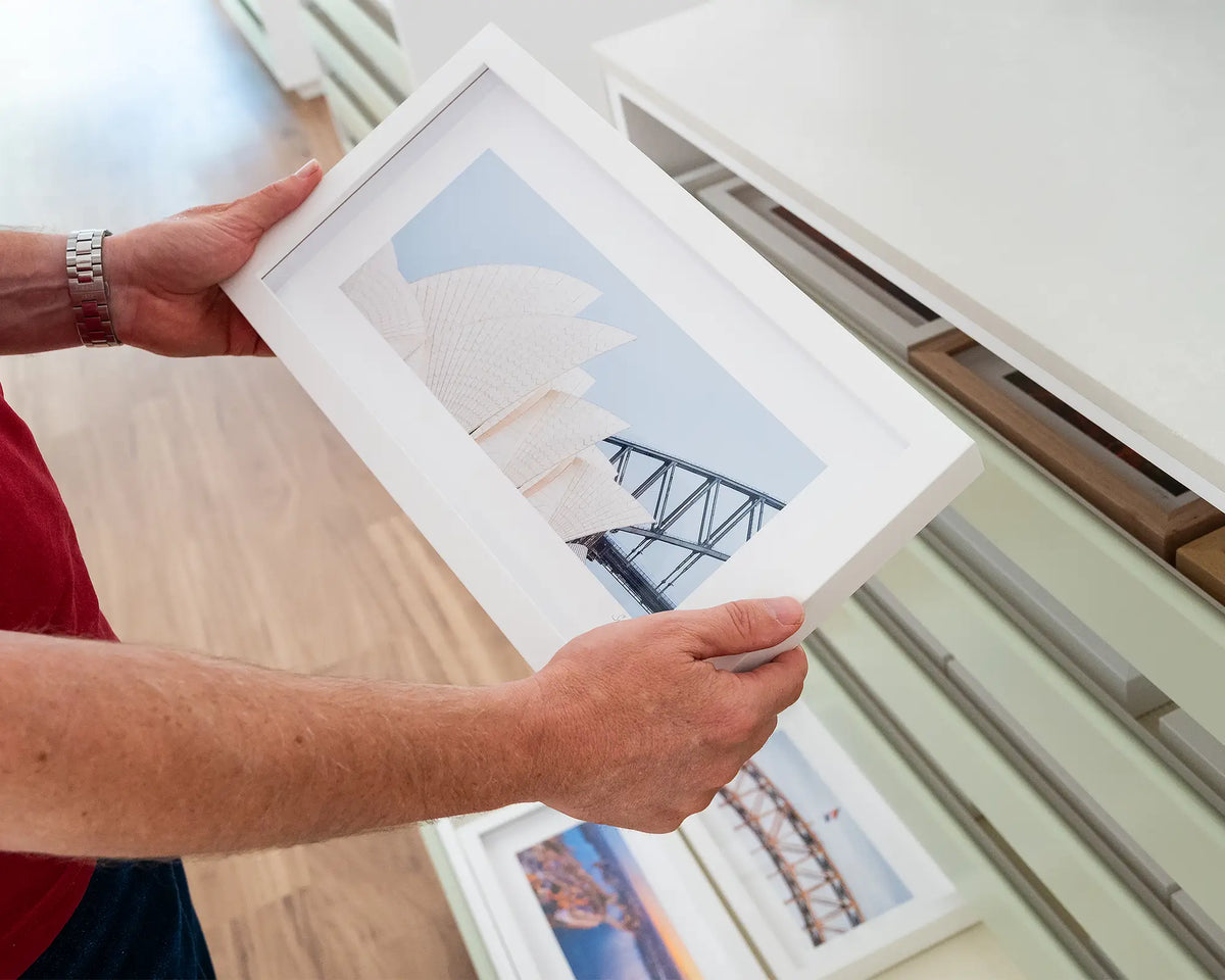 Sydney Outlines. Small framed print featuring the Opera House and Harbour Bridge, Sydney, hand held in gallery.