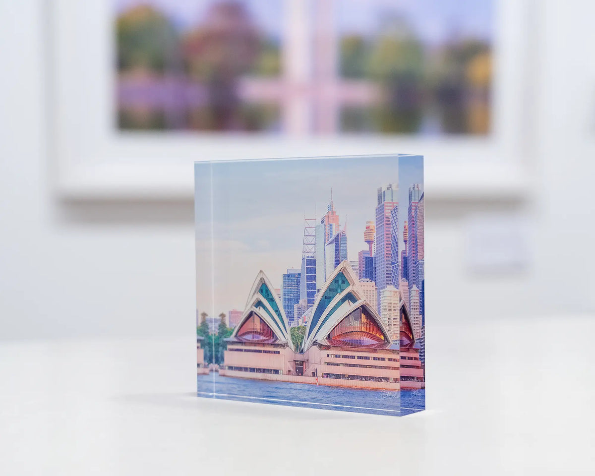 Sydney Views. Acrylic block sunset over Sydney Opera House, on gallery desk with artwork in background.