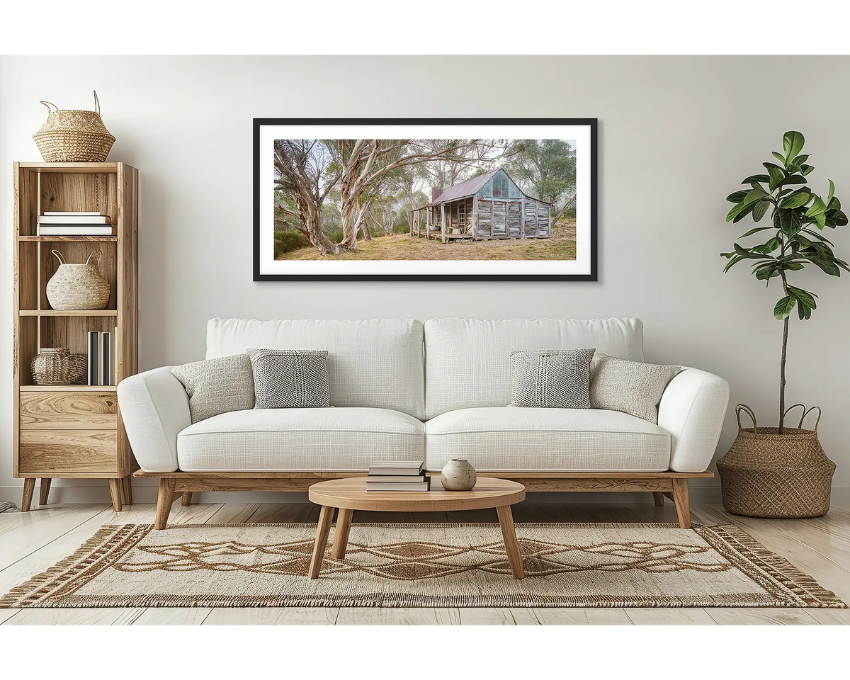 Tales of the Stockman. Wall art print of Wheelers Hut in Kosciuszko National Park with a black frame hung above a couch.