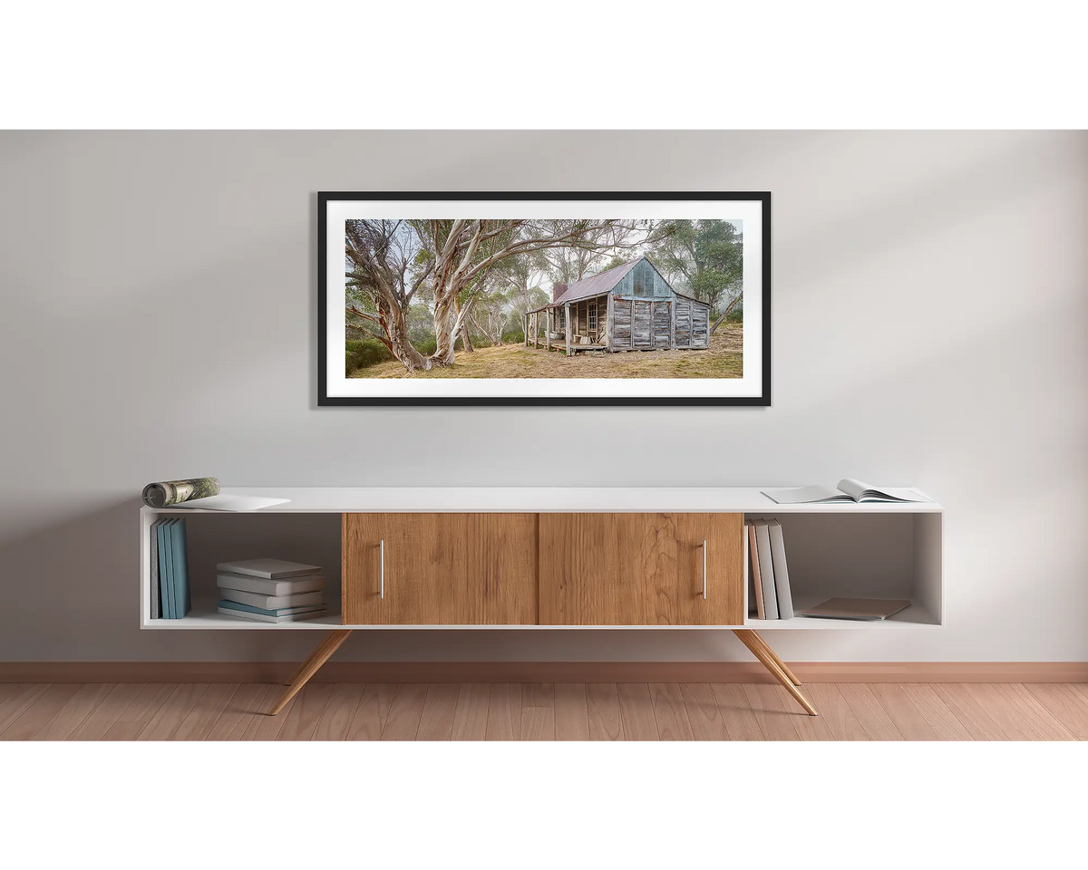 Tales of the Stockman. Wall art print of Wheelers Hut in Kosciuszko National Park with a black frame hung above a side table.