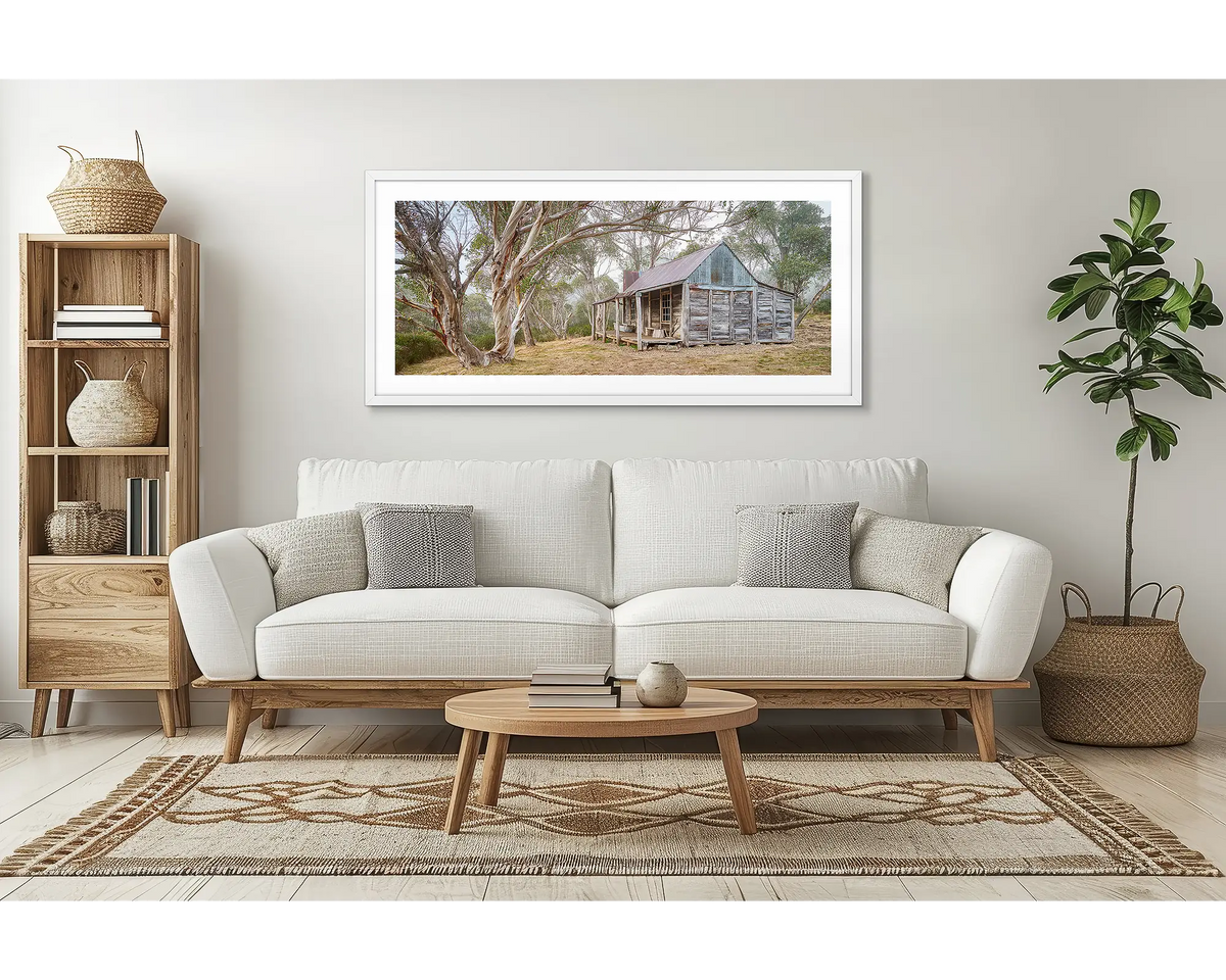 Tales of the Stockman. Wall art print of Wheelers Hut in Kosciuszko National Park with a white frame hung above a couch.