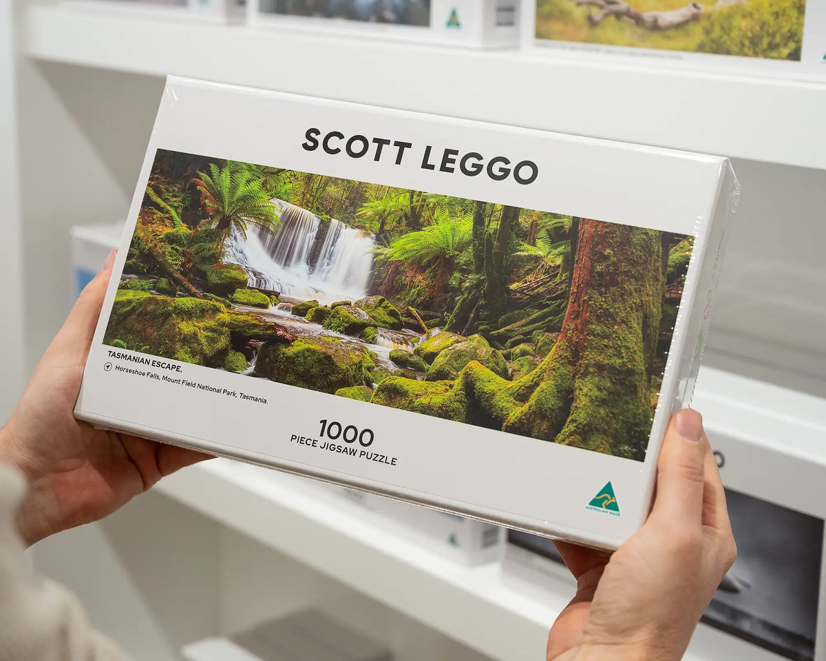 Tasmanian Escape 1000 piece jigsaw puzzle being held in front of other puzzle boxes.
