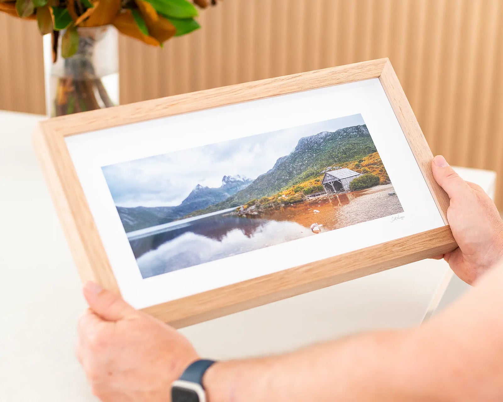 Framed photograph of a mountain landscape with a lake and wooden cabin at Cradle Mountain-Lake St Clair.
