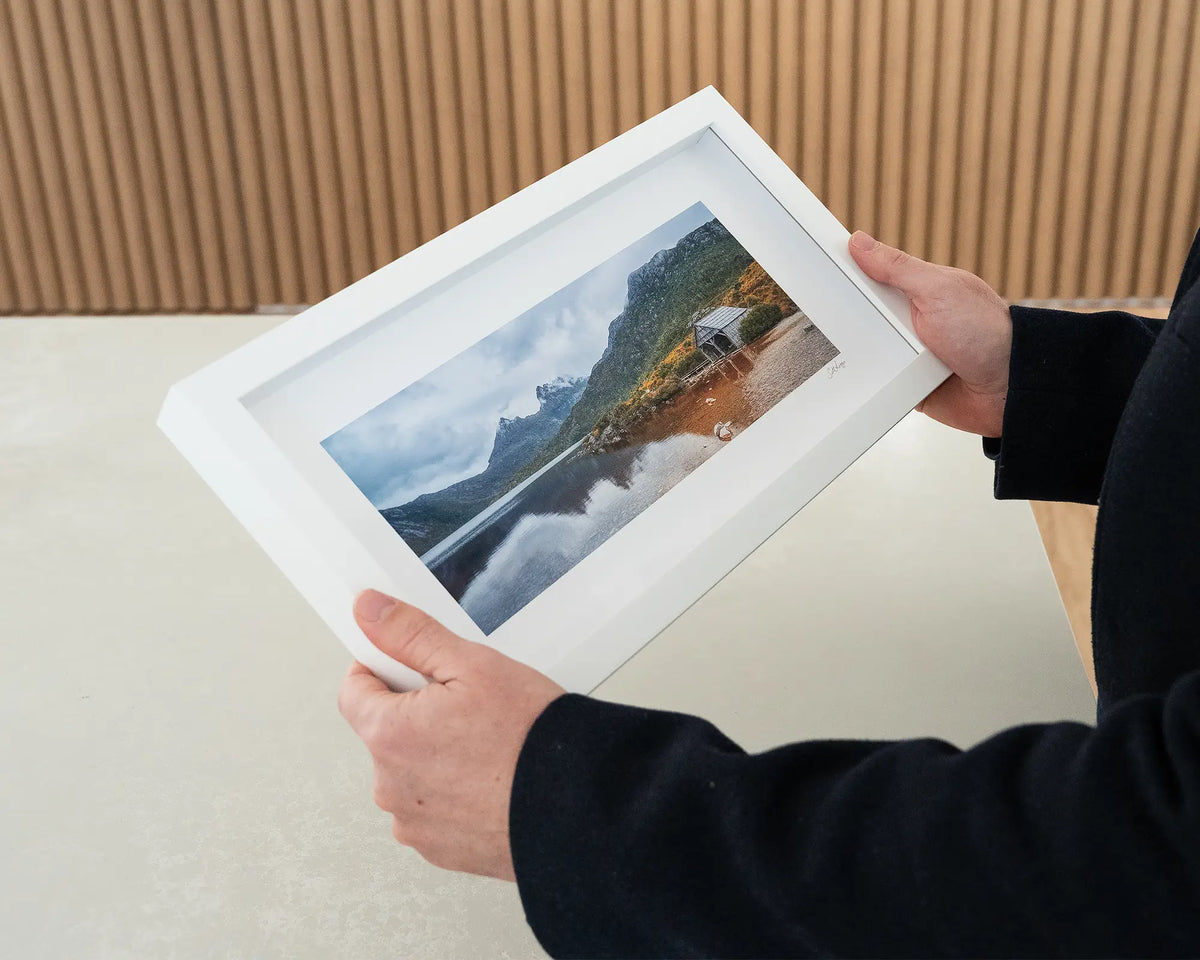 Tassie Icons. Cradle Mountain small framed print with white frame being hand held.