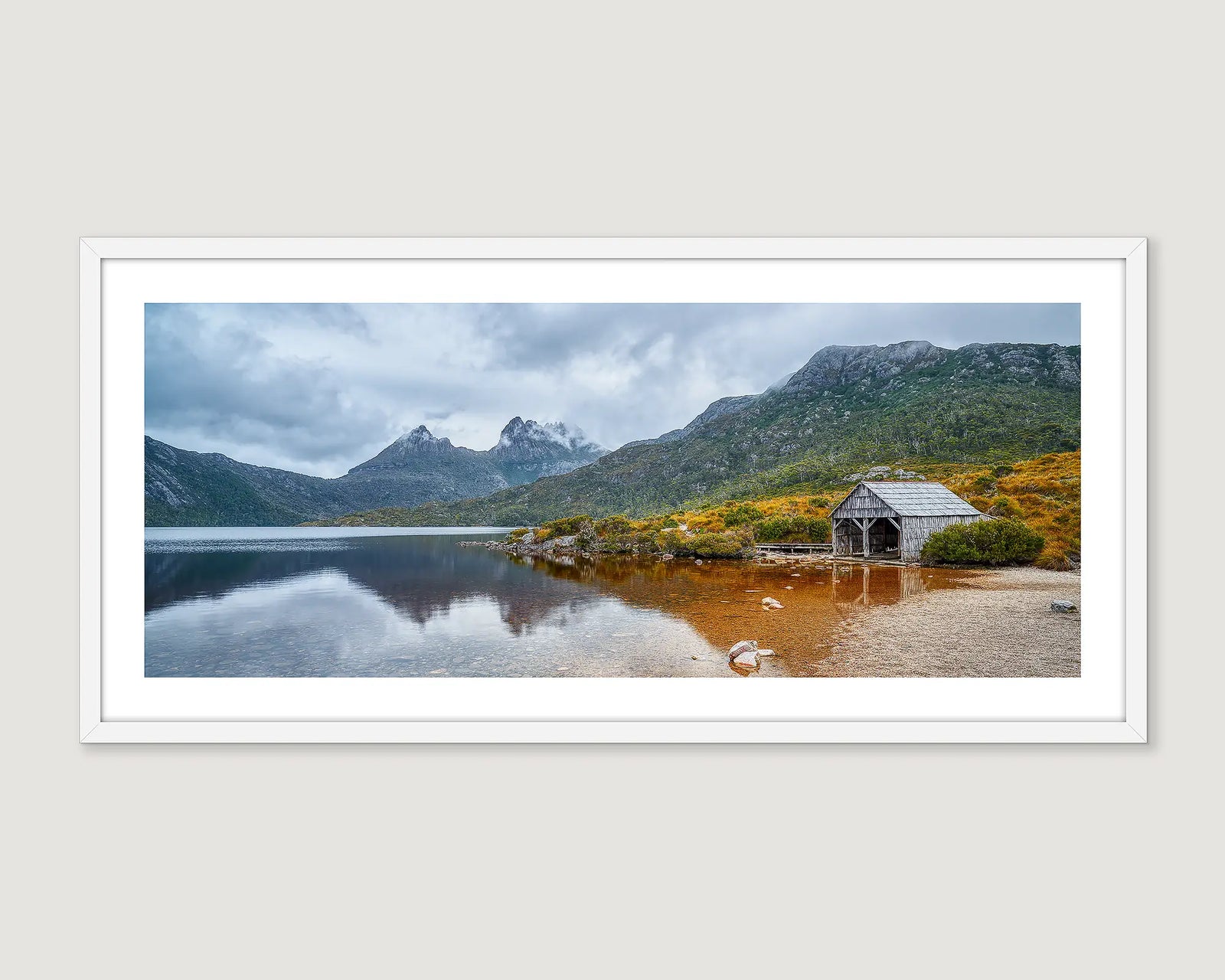 Framed photograph of a mountain landscape with a lake and wooden cabin at Cradle Mountain-Lake St Clair.