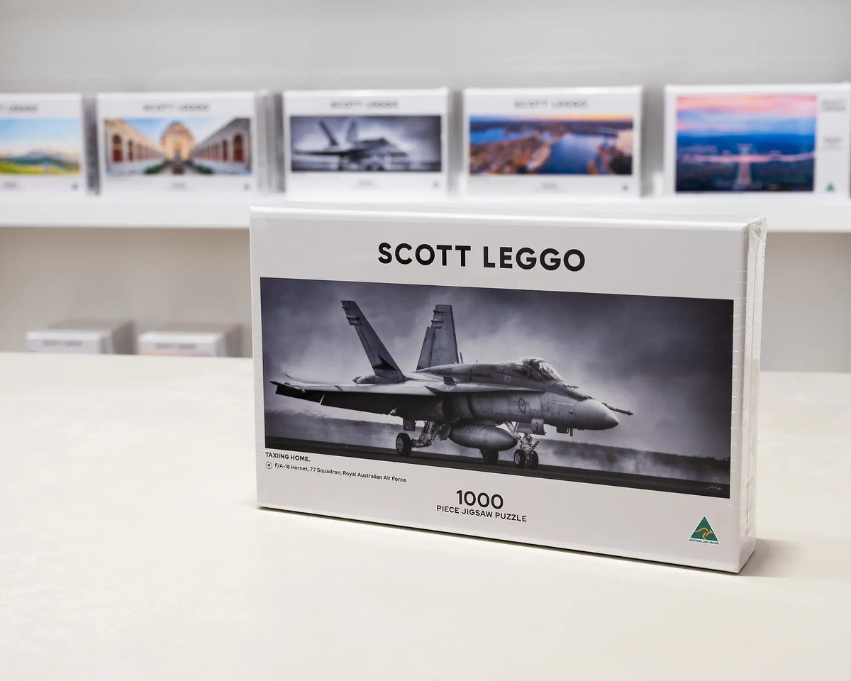 Taxiing Home 1000 piece aviation jigsaw puzzle box sitting on table in front of other puzzle boxes.