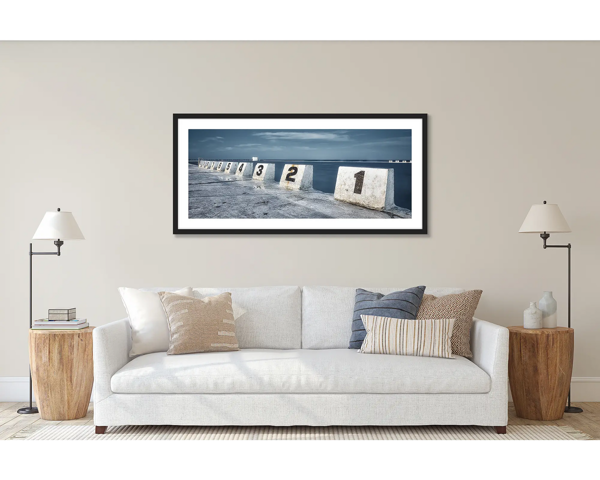 Ten. Merewether Baths, Newcastle, wall art print framed in a black frame, and hung above a couch. 