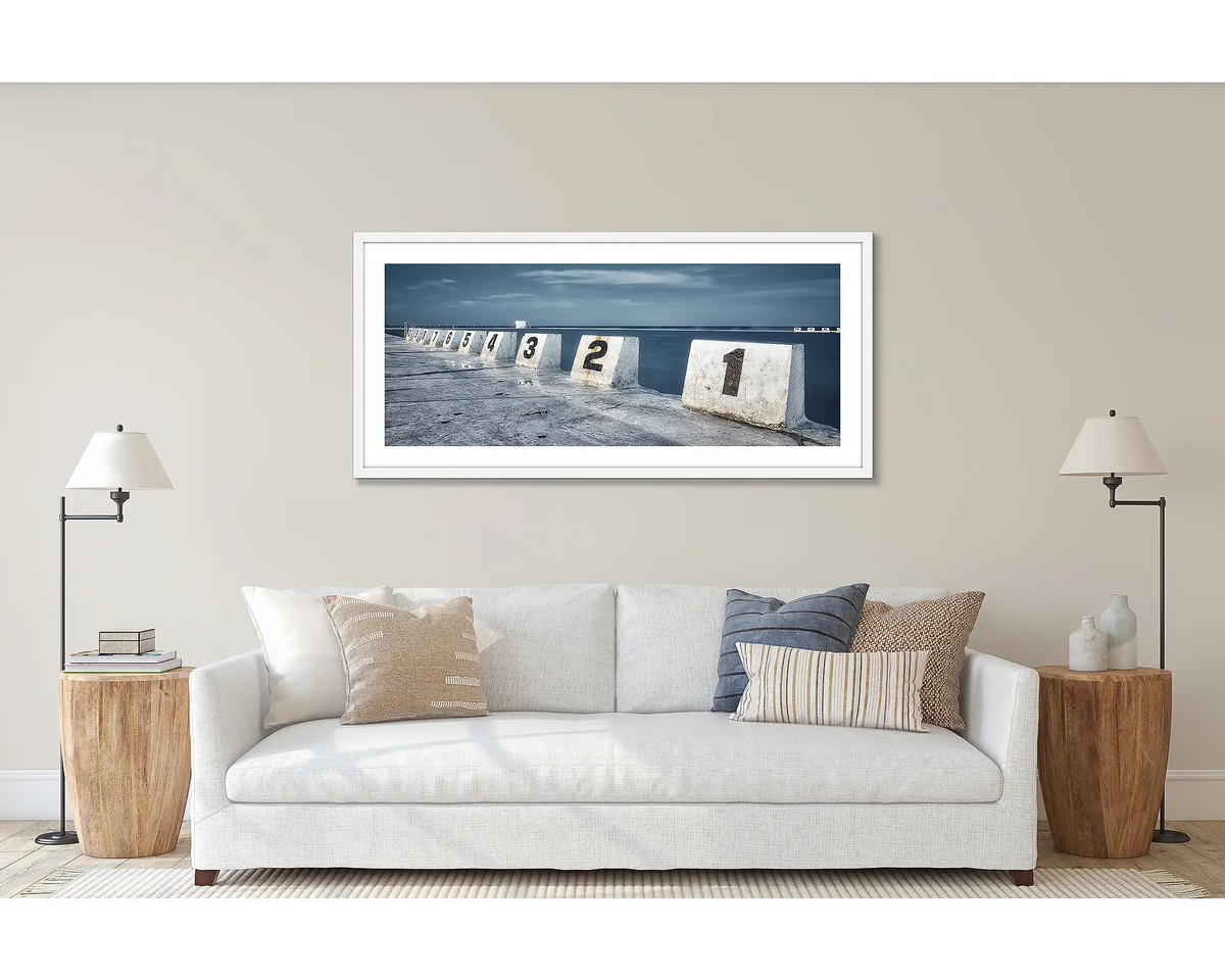 Ten. Merewether Baths, Newcastle, wall art print framed in a white frame, and hung above a couch. 