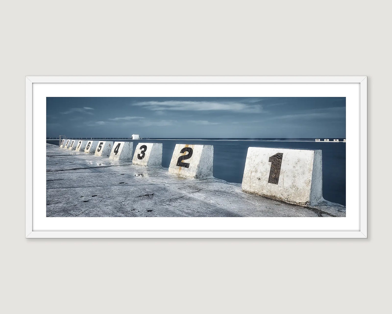 Framed photograph of numbered concrete blocks by a body of water at Merewether Ocean Baths.