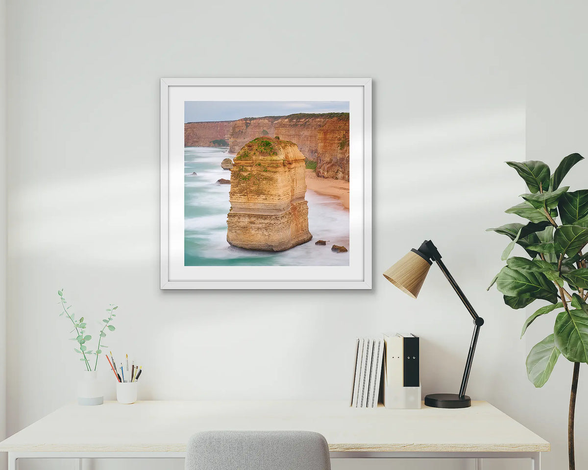 The Apostle. Great Ocean Road wall art print with a white frame hung above a small home office desk. 
