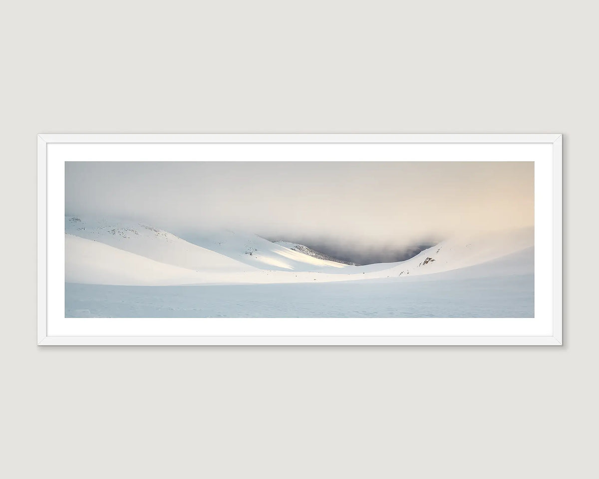Framed photograph of a snowy landscape with mountains and a cloudy sky.