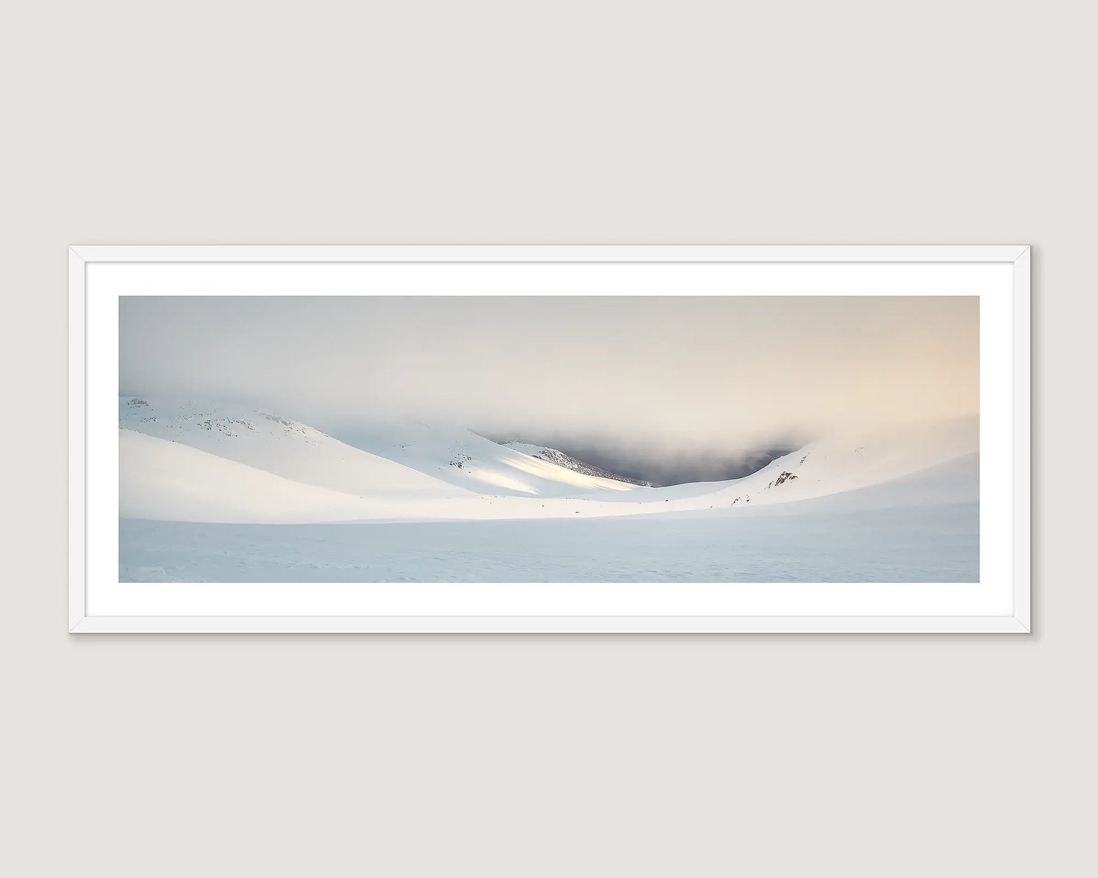 Framed photograph of a snowy landscape with mountains and a cloudy sky.