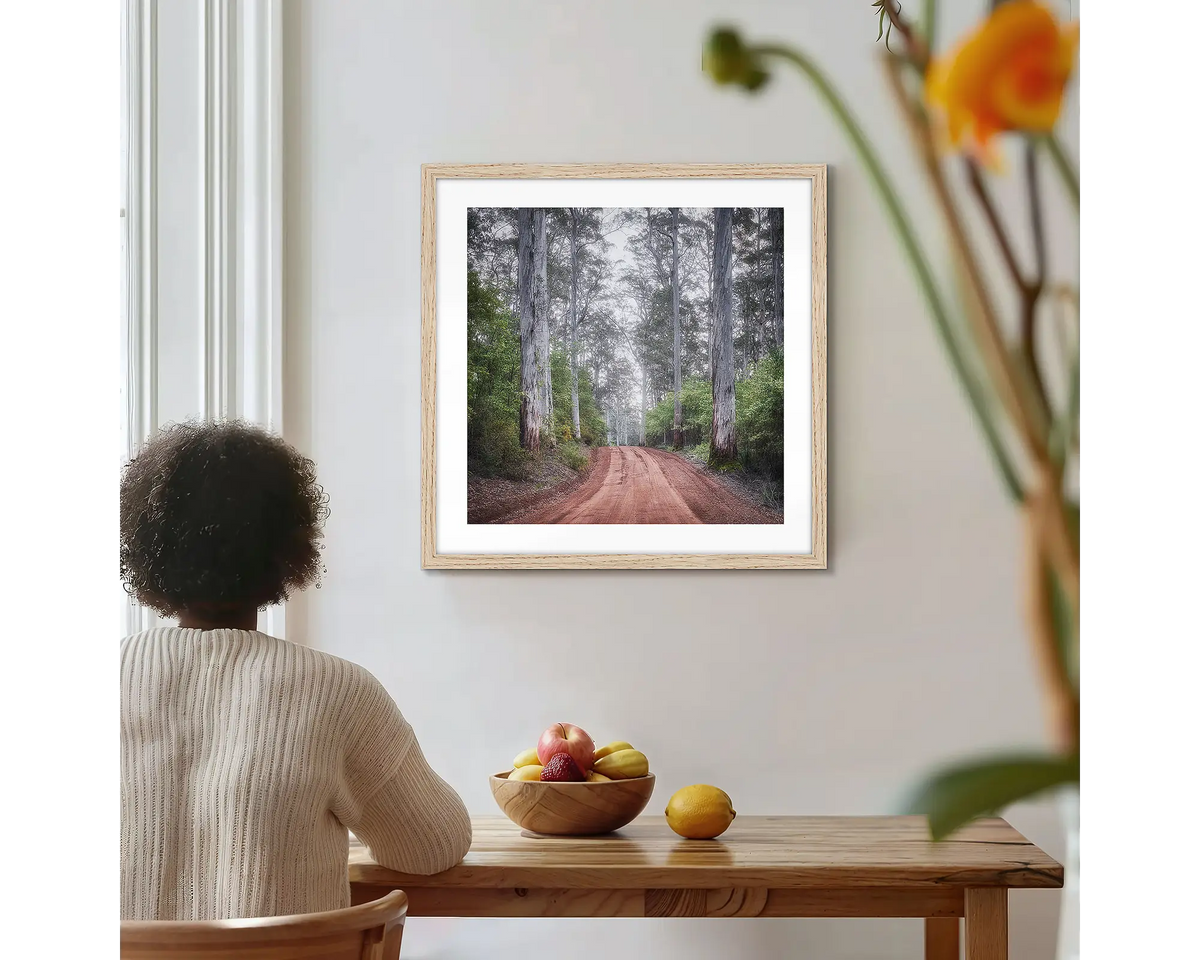 The Forest Beyond. Forest photographic wall art print with a timber frame, hung on a kitchen wall with a woman admiring. 