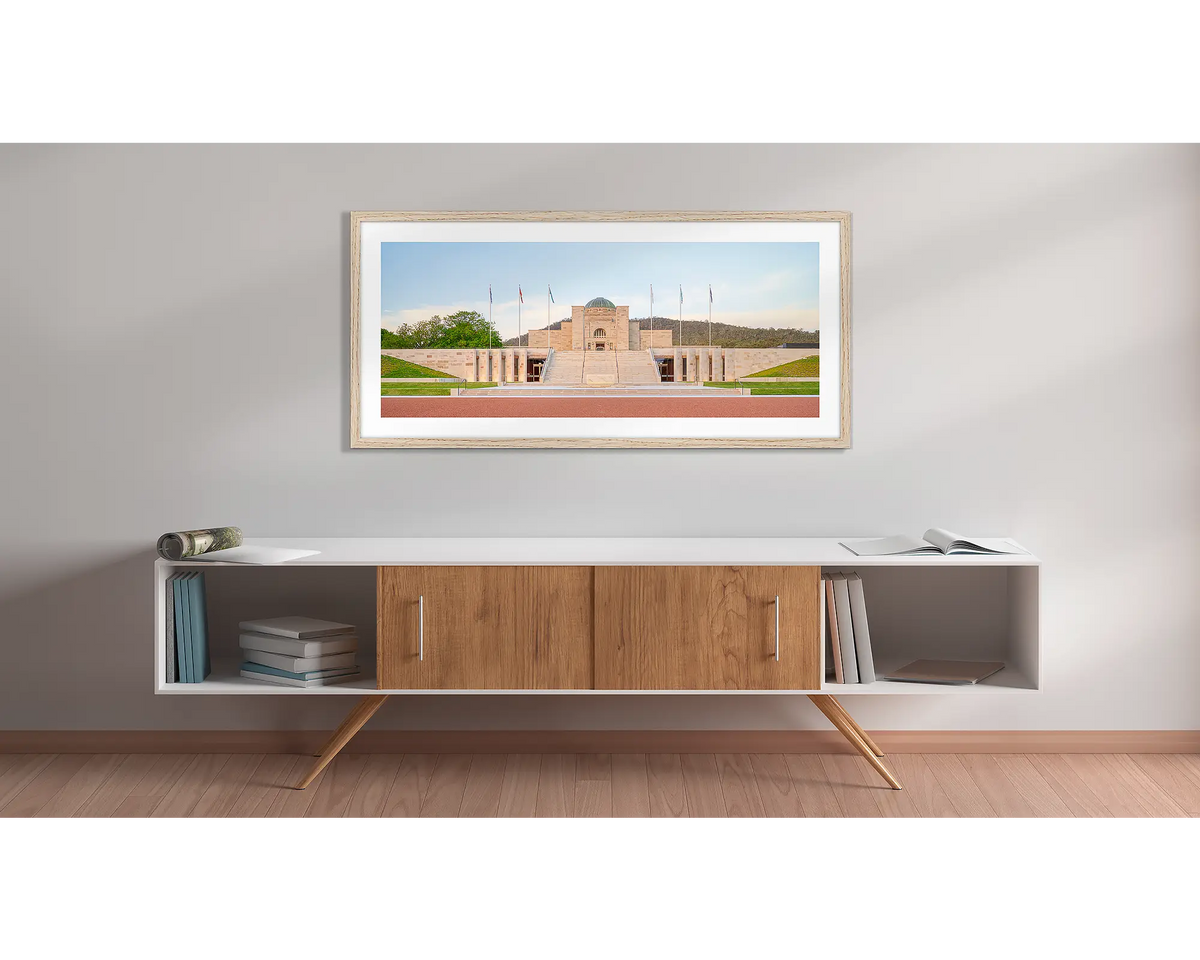 The Memorial. Wall art print with a timber frame, of the Australian War Memorial main entrance at sunset, hung above a side table. 