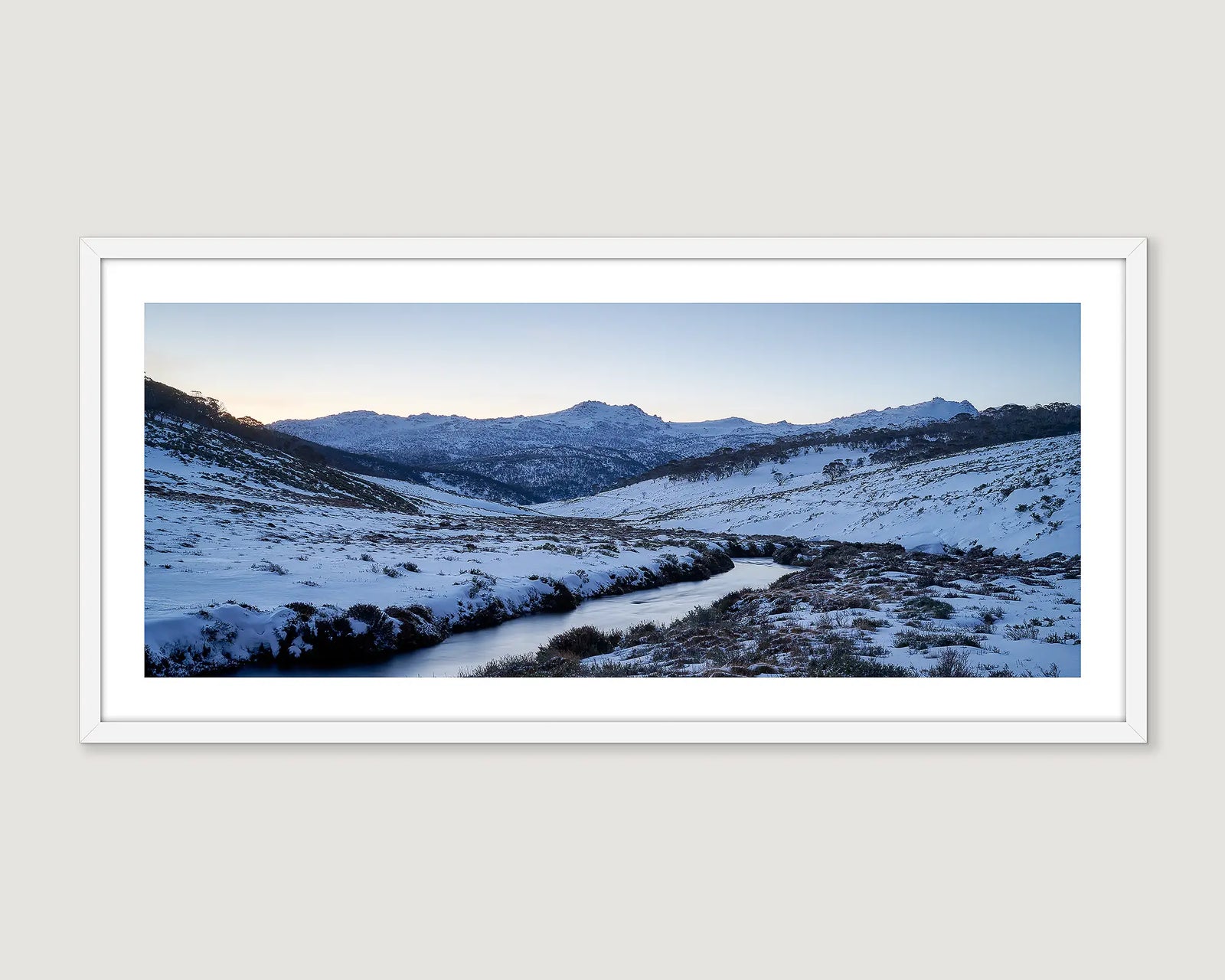 Framed photograph of a snowy Thredbo landscape with a river and mountains.