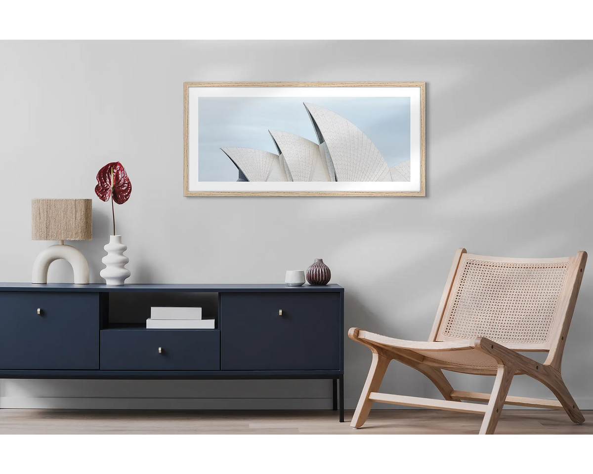 Tile Geometry. Wall art print featuring sails of the Sydney Opera House, with a timber frame, hung above a side table and chair. 