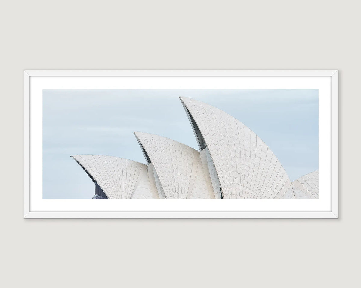 Framed photograph of the Sydney Opera House sails against a light blue sky.