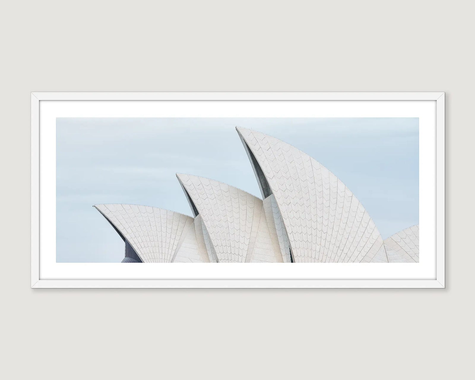Framed photograph of the Sydney Opera House sails against a light blue sky.