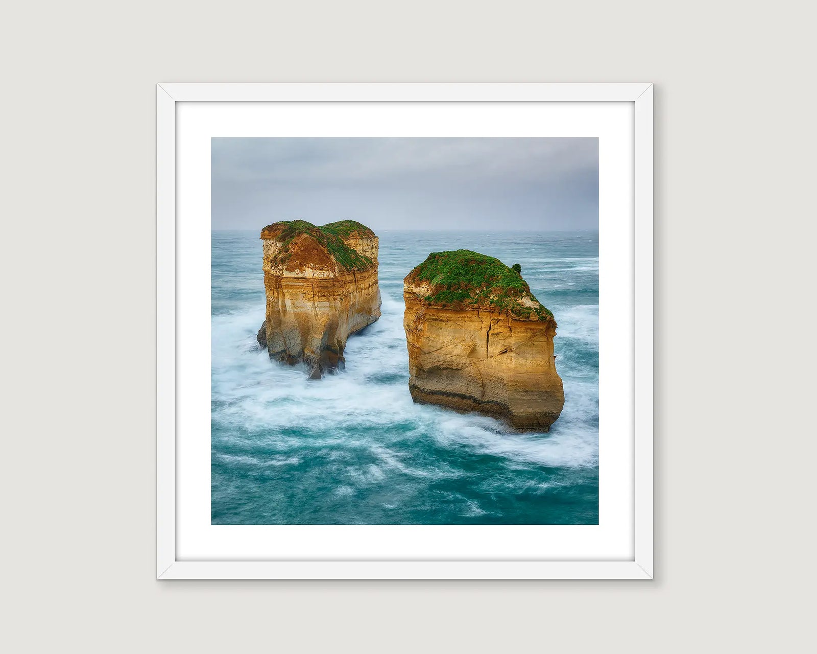 Framed photograph of two rock formations at the Great Ocean Road in the ocean with a white frame.