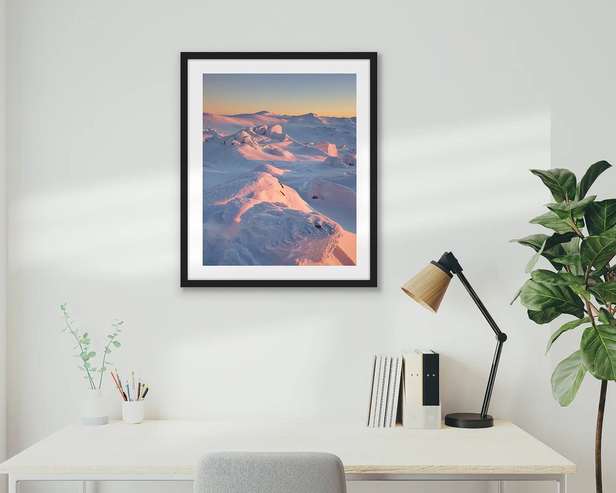 Tones of Kosciuszko. Wall art print of a sunrise over Mount Kosciuszko framed with a black frame and hung above a small desk. 