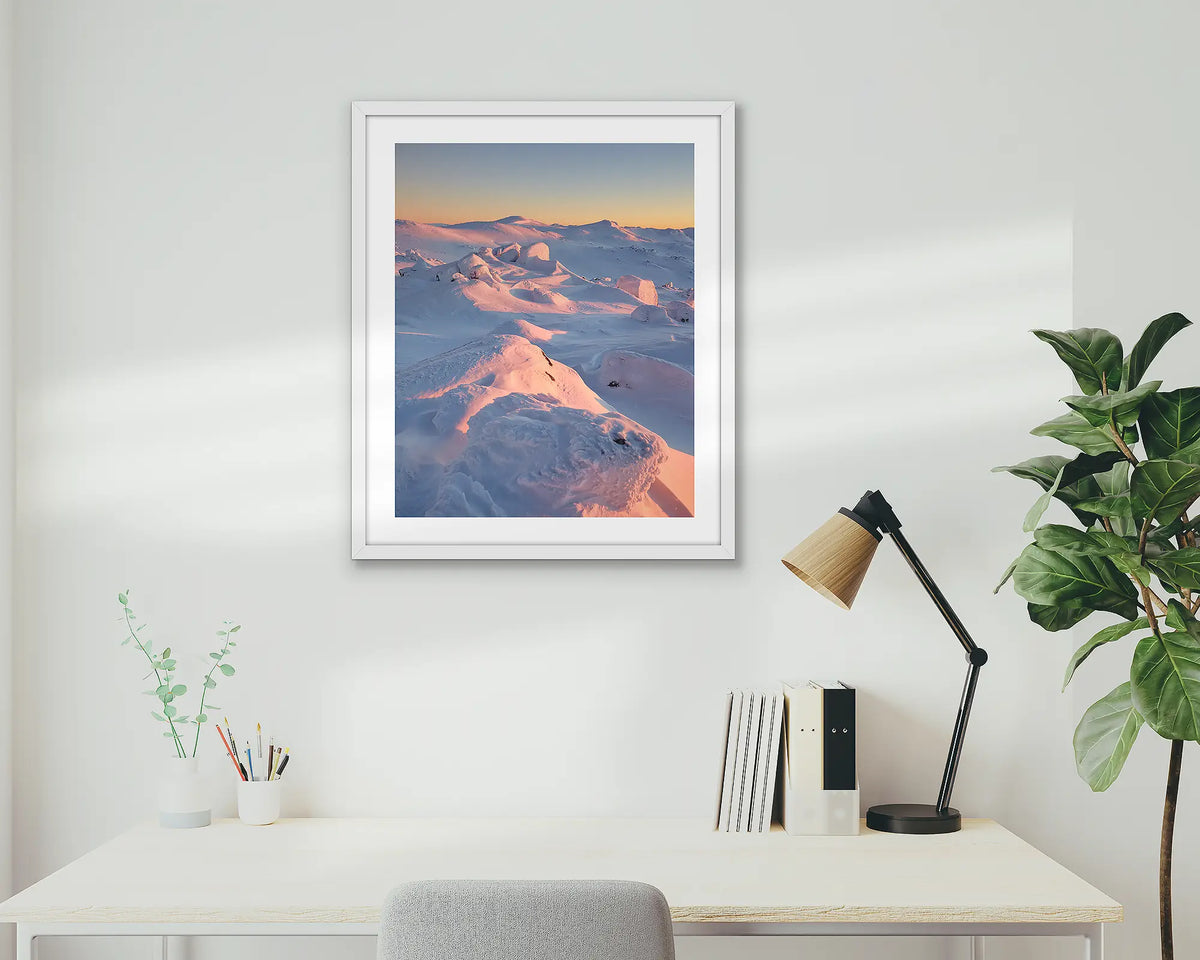 Tones of Kosciuszko. Wall art print of a sunrise over Mount Kosciuszko framed with a white frame and hung above a small desk. 