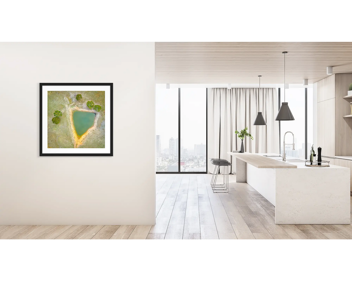 Trigonous. Framed wall art print of a farm dam, in Brindabella Valley, with a black frame hung on a hallway wall. 