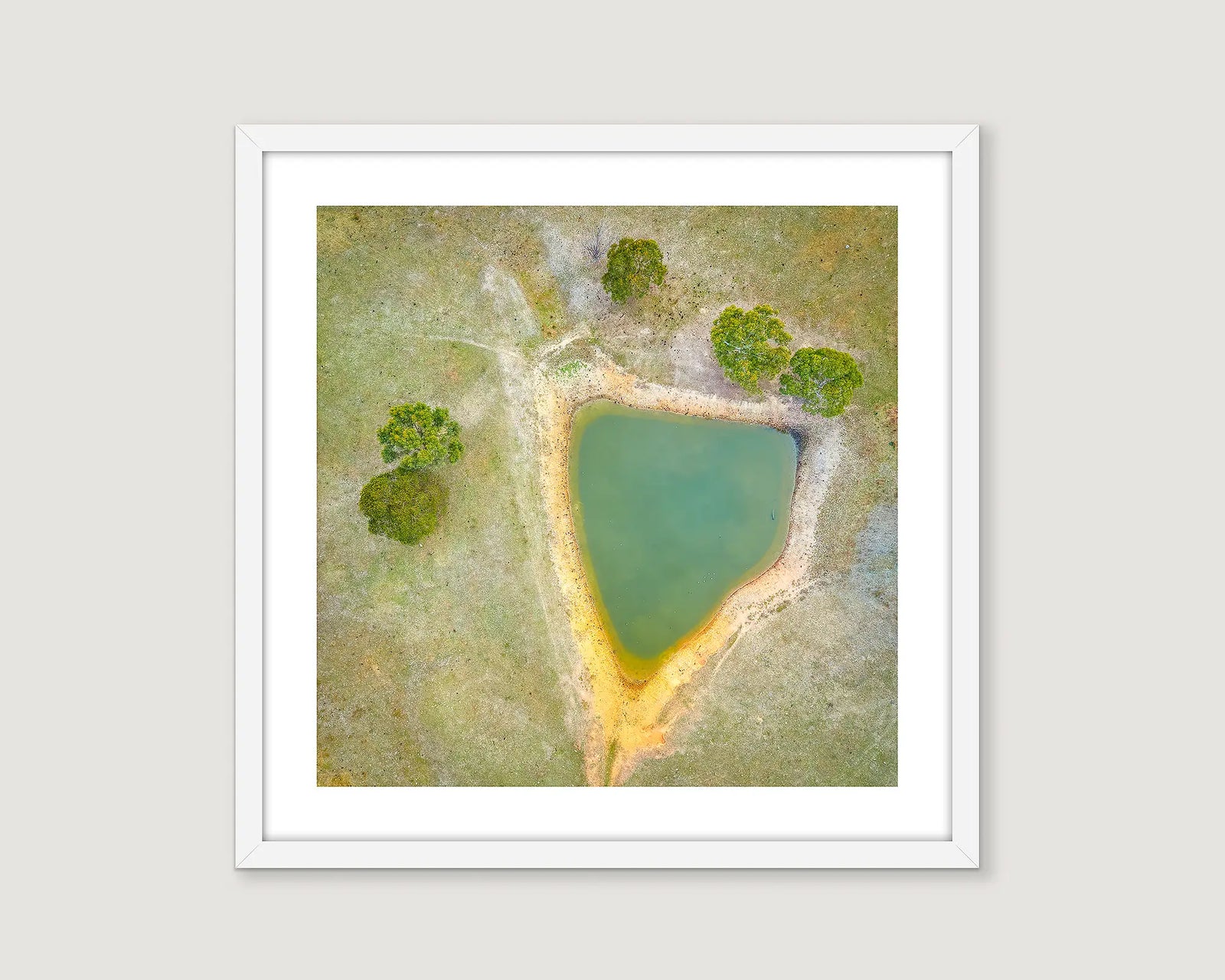 Framed abstract artwork of a triangular shaped pond with trees.