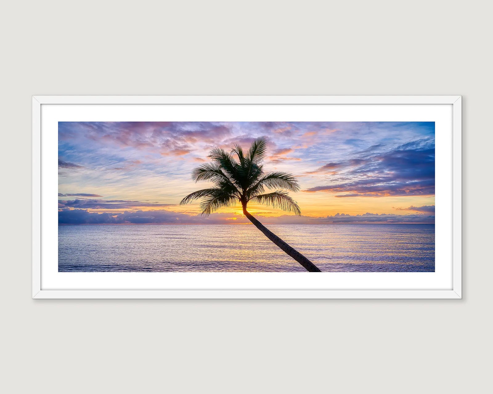 Framed artwork of a palm tree at sunset over water.