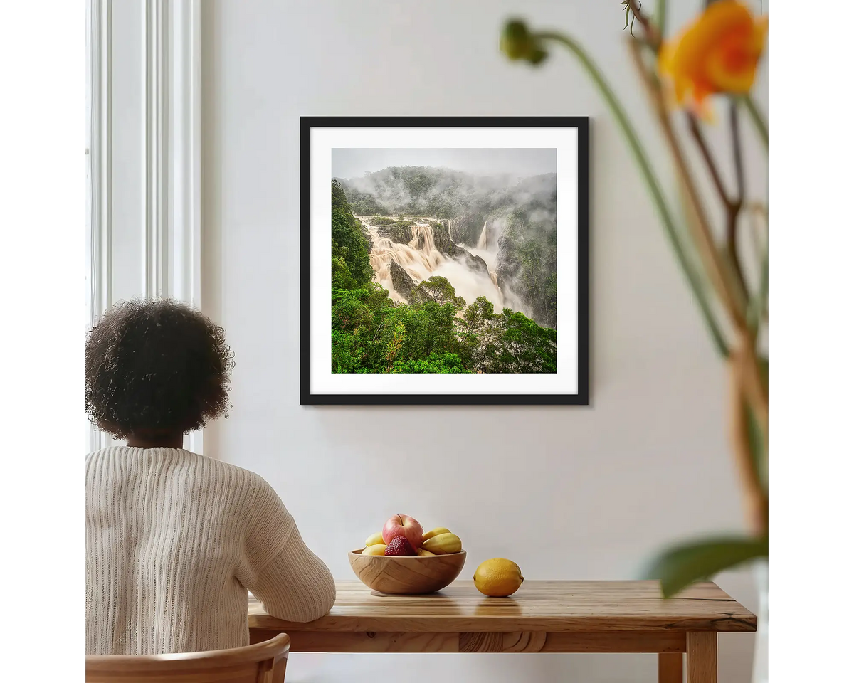 Tropical Pour. Barron Falls photographic wall art print with a black frame, hung on a kitchen wall with a woman admiring. 