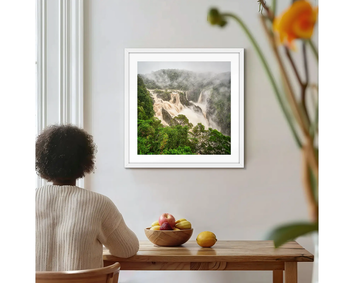 Tropical Pour. Barron Falls photographic wall art print with a white frame, hung on a kitchen wall with a woman admiring. 