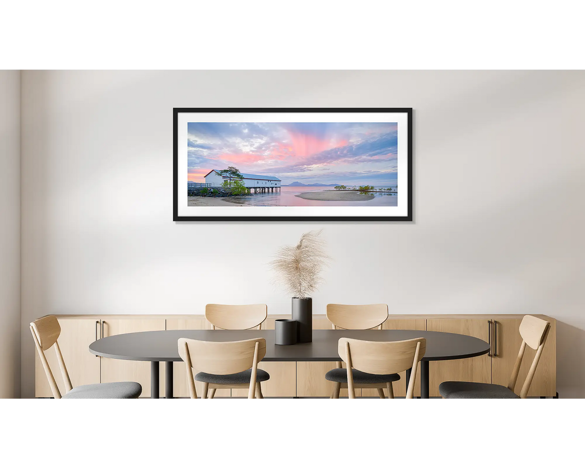 Twilight Blush. Wall art print of a pink sunset over Port Douglas, framed in a black frame and hung on a dining room wall. 