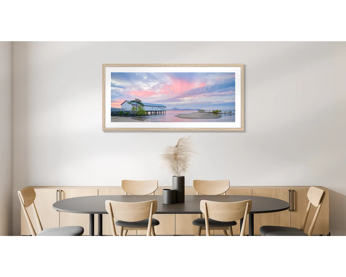 Twilight Blush. Wall art print of a pink sunset over Port Douglas, framed in a timber frame and hung on a dining room wall. 