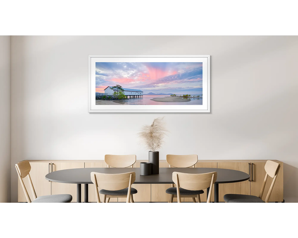 Twilight Blush. Wall art print of a pink sunset over Port Douglas, framed in a white frame and hung on a dining room wall. 