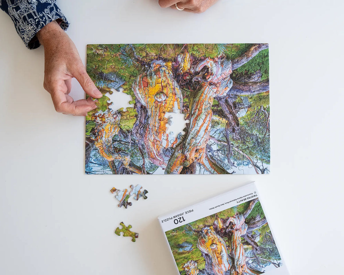 Twisted Beauty. 120 piece jigsaw puzzle of a colourful snow gum Kosciuszko National Park, being assembled on a desk.