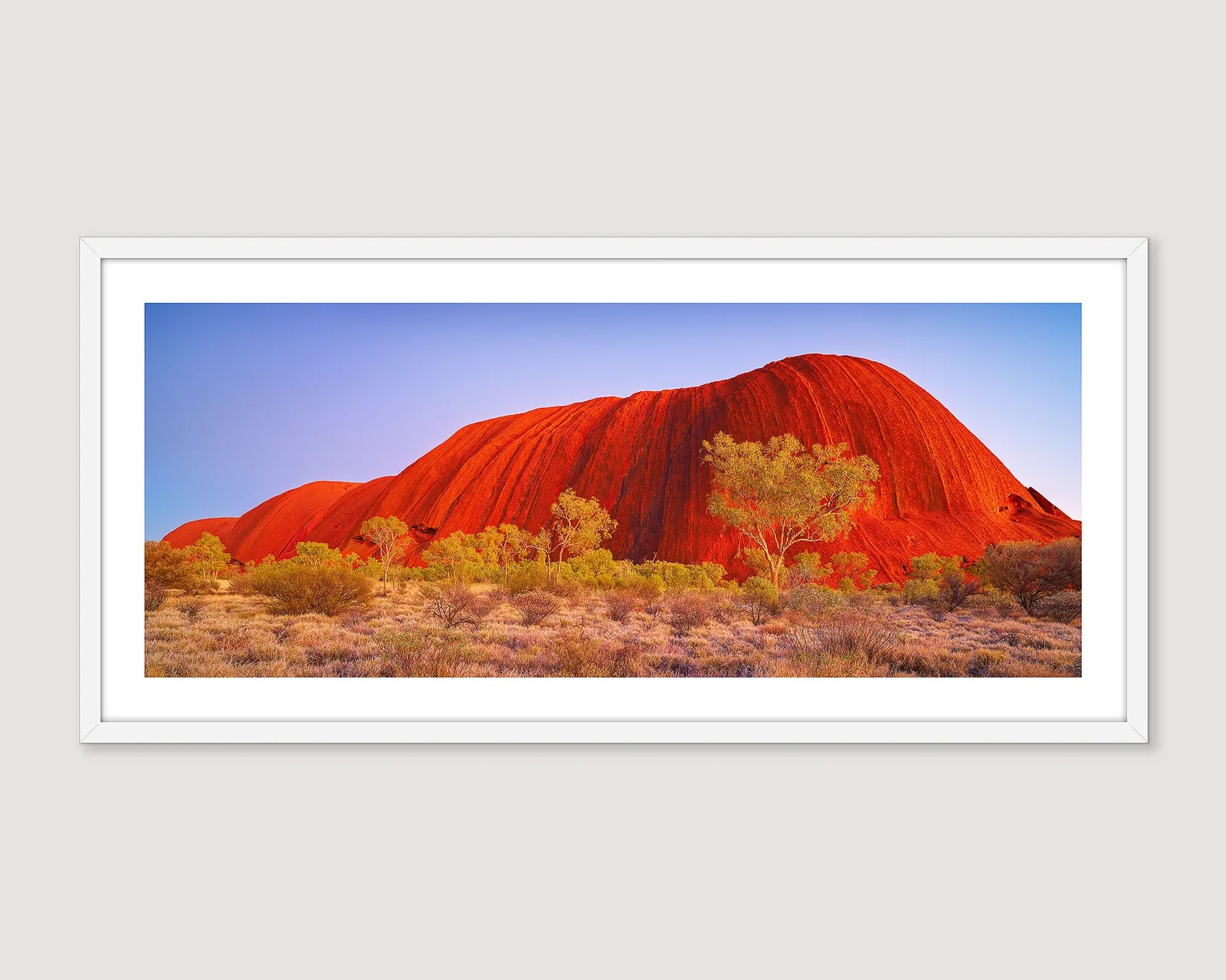 Framed photograph of a Uluru with trees against a blue sky.